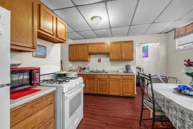 kitchen with white appliances, sink, a paneled ceiling, and dark wood-type flooring