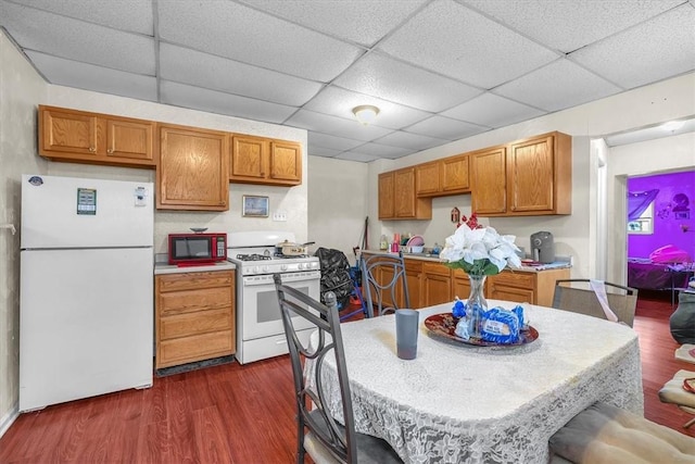 kitchen featuring white appliances, dark hardwood / wood-style floors, and a drop ceiling