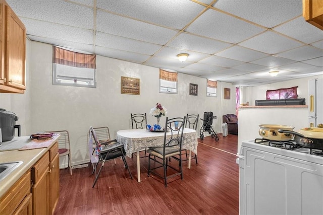 dining space with a paneled ceiling and dark hardwood / wood-style flooring