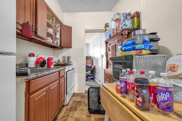 kitchen featuring sink, light tile patterned flooring, a textured ceiling, and white appliances