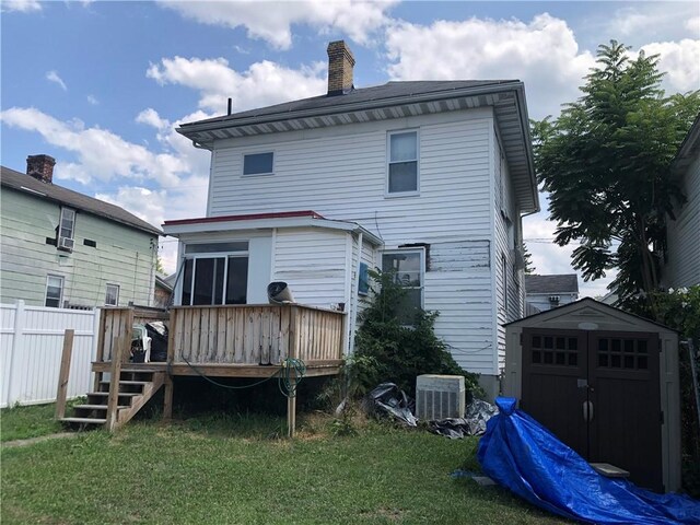 rear view of house with a storage unit, a lawn, and a wooden deck