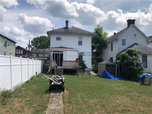 back of house featuring a deck, an outdoor structure, and a yard