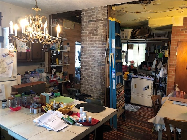 interior space featuring a notable chandelier, washer / dryer, and brick wall