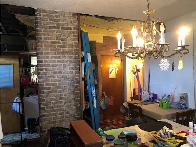 dining space featuring a notable chandelier and brick wall