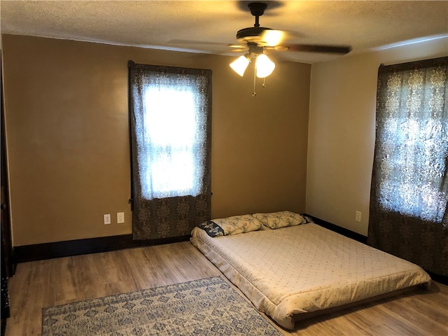 bedroom featuring a textured ceiling, wood-type flooring, and ceiling fan