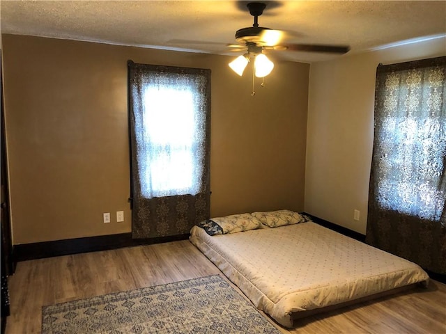 bedroom with hardwood / wood-style floors, a textured ceiling, and ceiling fan