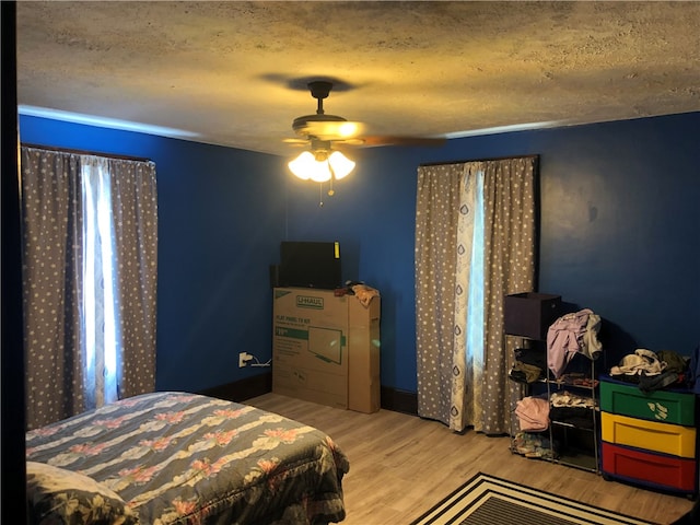 bedroom with hardwood / wood-style flooring, a textured ceiling, and ceiling fan