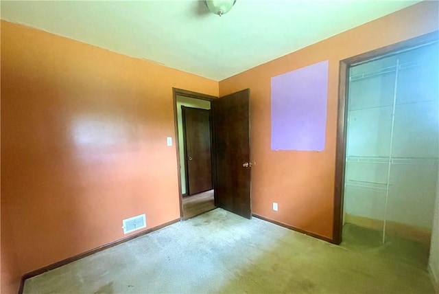 unfurnished bedroom with light colored carpet and a closet