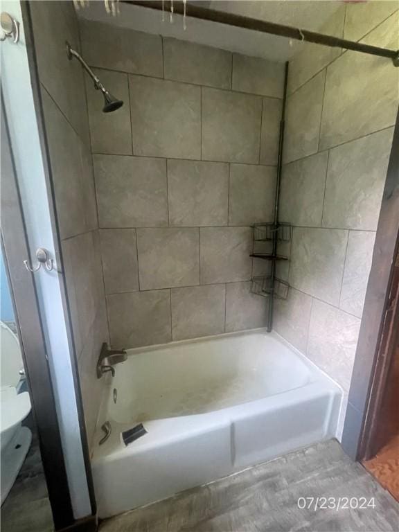 bathroom with tiled shower / bath combo and toilet