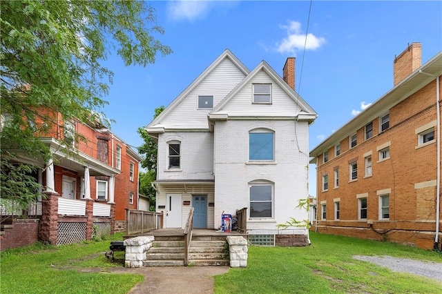 view of front of property featuring a front lawn, brick siding, and a chimney