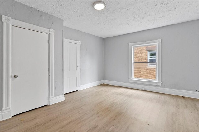 spare room with light wood-type flooring and a textured ceiling