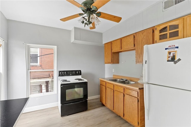 kitchen with light wood-style flooring, range with electric stovetop, freestanding refrigerator, and a sink