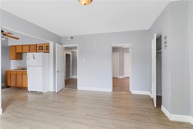 unfurnished living room with visible vents, baseboards, light wood-style floors, and a ceiling fan