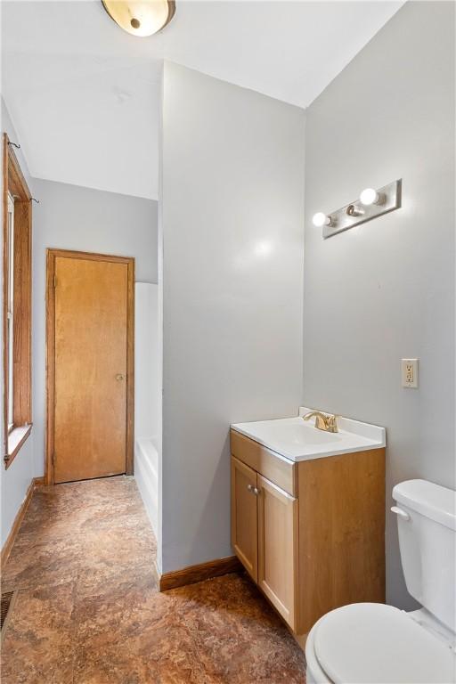 full bath with vanity, toilet, baseboards, and a tub