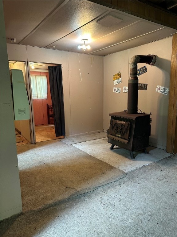 unfurnished room featuring a wood stove and carpet flooring