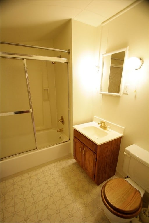 full bathroom featuring tile patterned flooring, toilet, shower / bath combination with glass door, and vanity