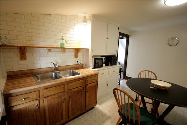 kitchen with sink, white cabinets, backsplash, and light tile patterned floors