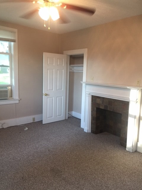 unfurnished living room with carpet flooring, a fireplace, and ceiling fan