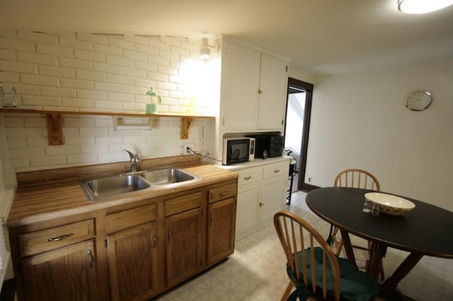 kitchen featuring white cabinets, light tile patterned floors, tasteful backsplash, and sink