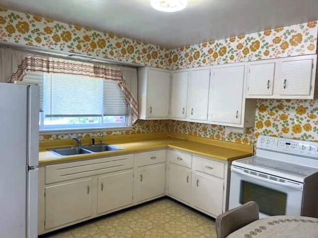 kitchen featuring sink, white cabinetry, light tile patterned floors, and white appliances