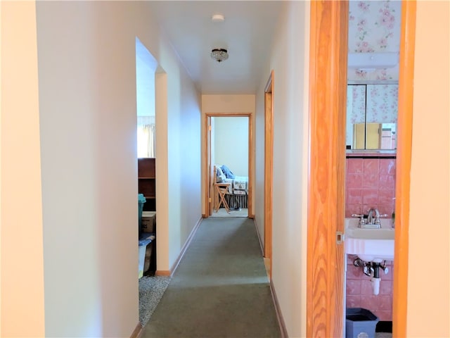 hall with sink, carpet, and tile walls