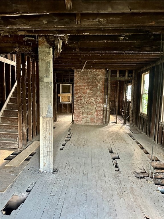 misc room with brick wall and wood-type flooring