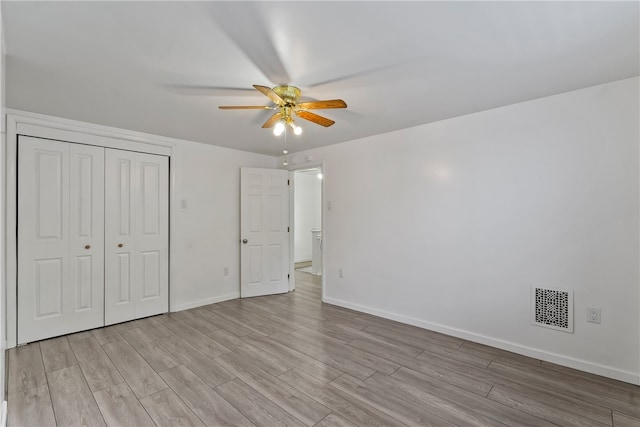 unfurnished bedroom featuring light hardwood / wood-style flooring, ceiling fan, and a closet