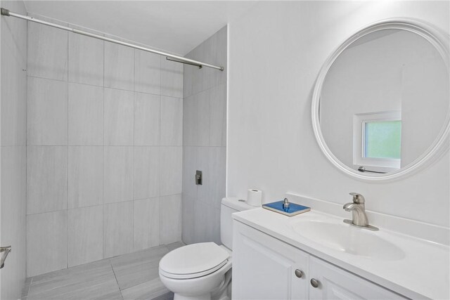 bathroom featuring toilet, vanity, and a tile shower