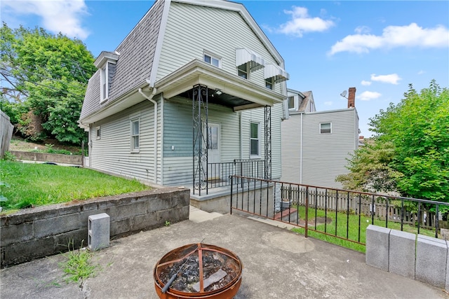 back of house with a fire pit and a yard