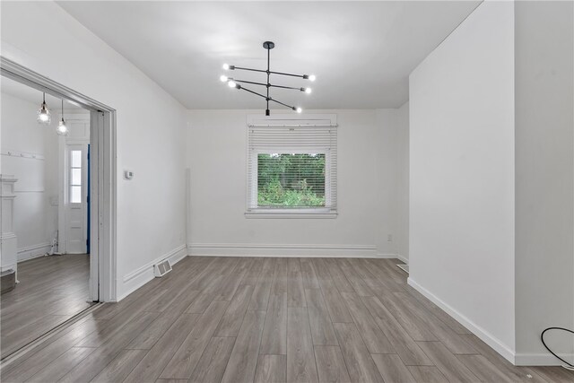 empty room featuring light hardwood / wood-style flooring and a chandelier