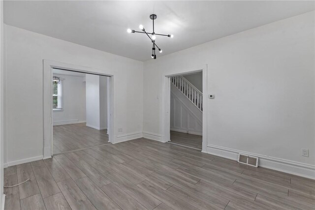 unfurnished room with light hardwood / wood-style flooring and an inviting chandelier