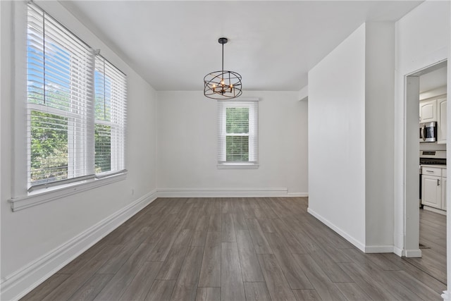 unfurnished room featuring plenty of natural light, an inviting chandelier, and hardwood / wood-style flooring