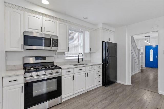 kitchen with white cabinetry, light hardwood / wood-style flooring, appliances with stainless steel finishes, and sink