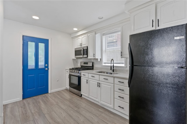 kitchen featuring sink, white cabinets, light wood-type flooring, and stainless steel appliances