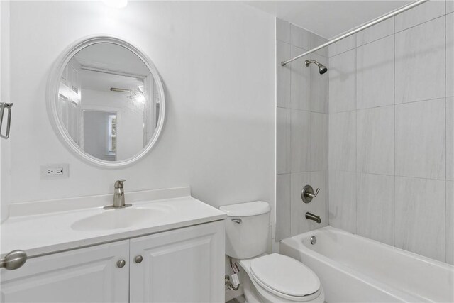 full bathroom featuring vanity, tiled shower / bath combo, and toilet