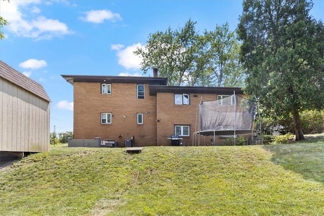 rear view of house featuring a lawn and a trampoline