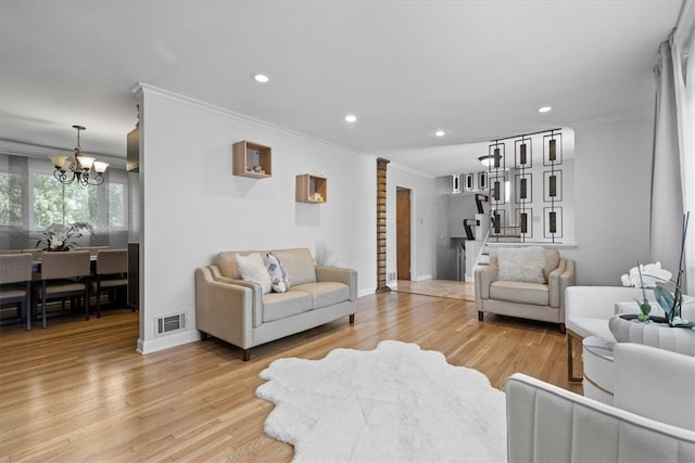 living room featuring crown molding, light hardwood / wood-style flooring, and an inviting chandelier