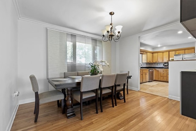 dining area with crown molding, light hardwood / wood-style flooring, and a notable chandelier