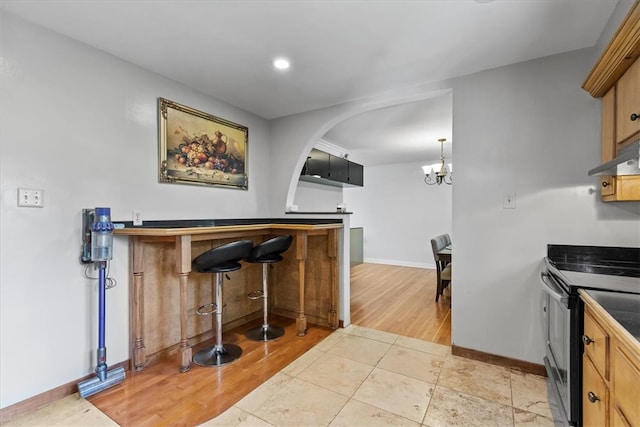 kitchen with light tile patterned floors, pendant lighting, stainless steel range with electric stovetop, and an inviting chandelier