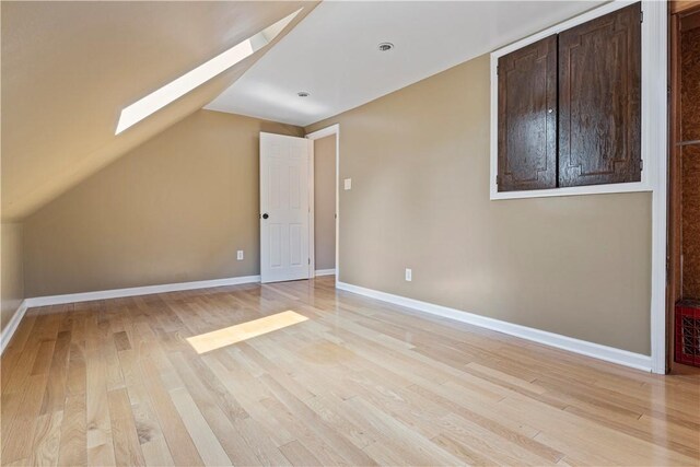 bonus room with lofted ceiling with skylight and light hardwood / wood-style floors