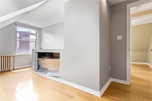 hall featuring lofted ceiling, light hardwood / wood-style flooring, and radiator heating unit