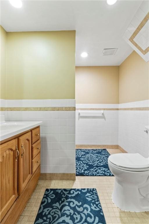 bathroom featuring tile walls, tile patterned floors, toilet, and vanity