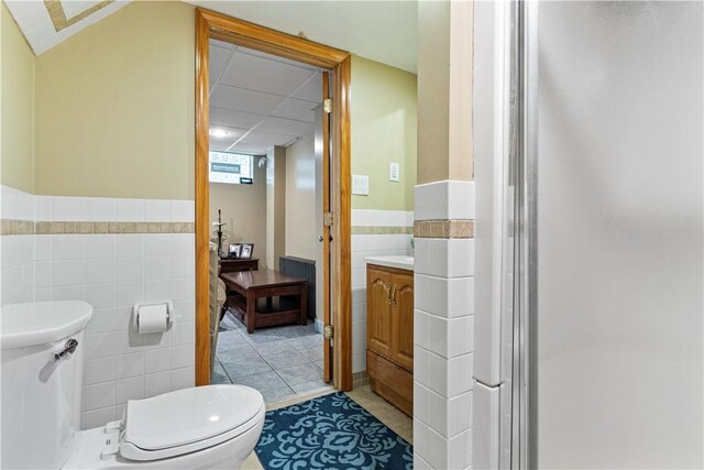 bathroom with tile patterned floors, vanity, tile walls, and toilet