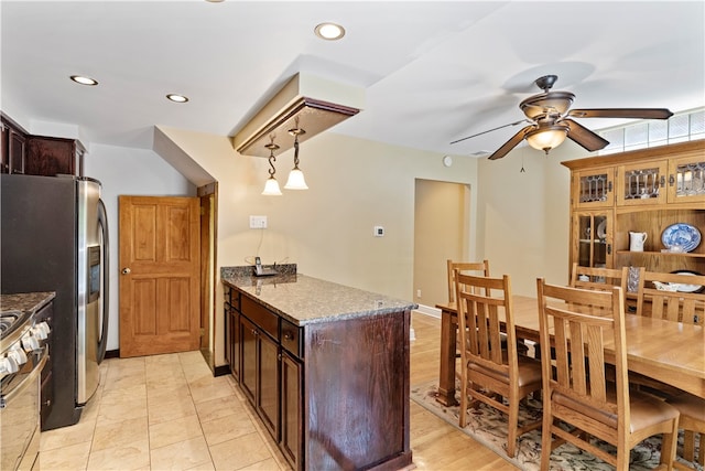 kitchen with ceiling fan, stainless steel appliances, light hardwood / wood-style floors, light stone countertops, and hanging light fixtures