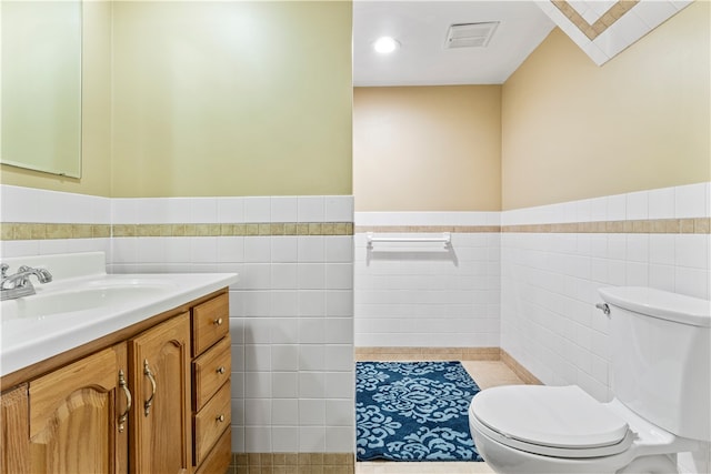 bathroom featuring vanity, tile walls, toilet, and tile patterned flooring