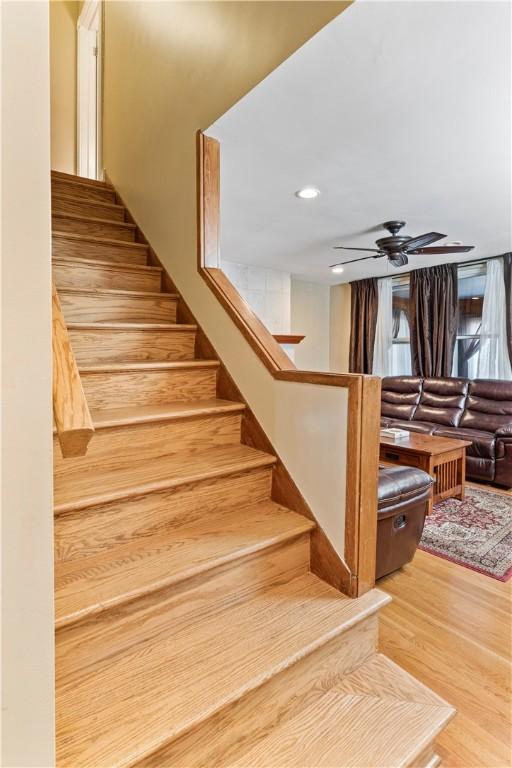 staircase featuring ceiling fan and wood-type flooring