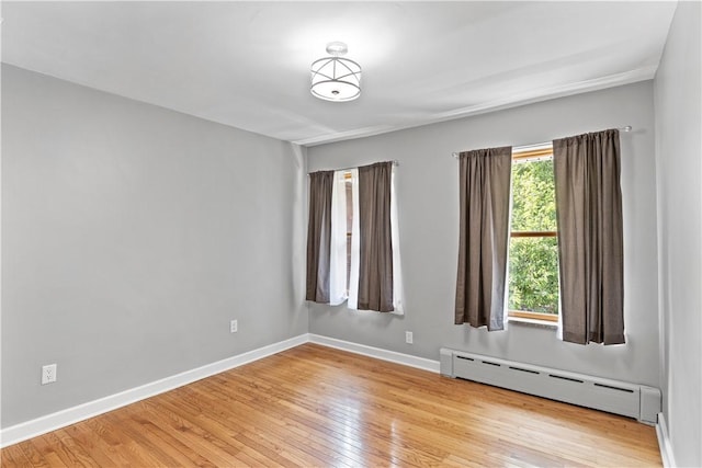 empty room featuring a baseboard radiator, light wood-type flooring, and a wealth of natural light