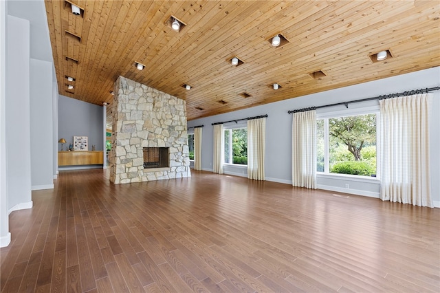 unfurnished living room with high vaulted ceiling, a stone fireplace, hardwood / wood-style floors, and wood ceiling