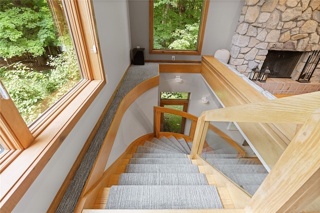 stairs featuring a fireplace and a healthy amount of sunlight