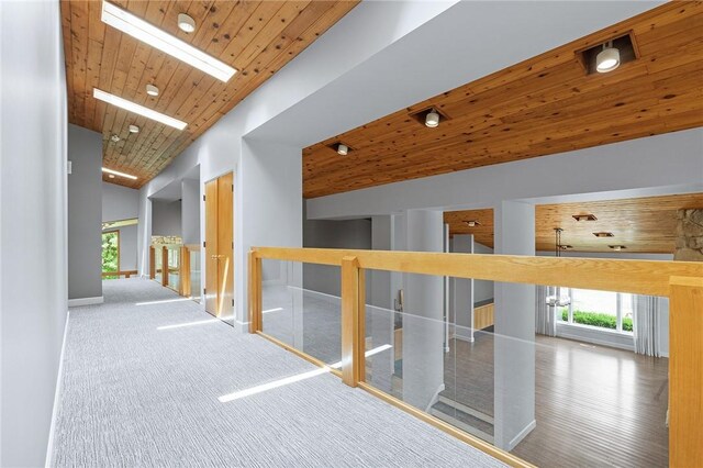 hallway with vaulted ceiling with skylight and wooden ceiling